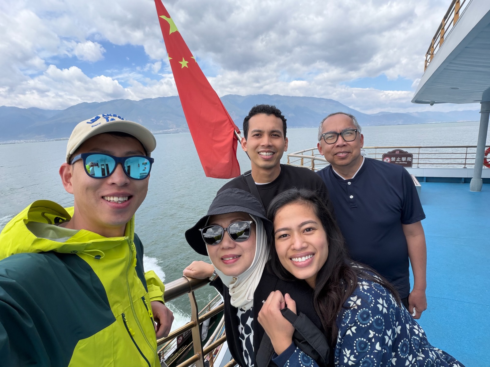 Five travelers taking a group photo on an Erhai Lake boat