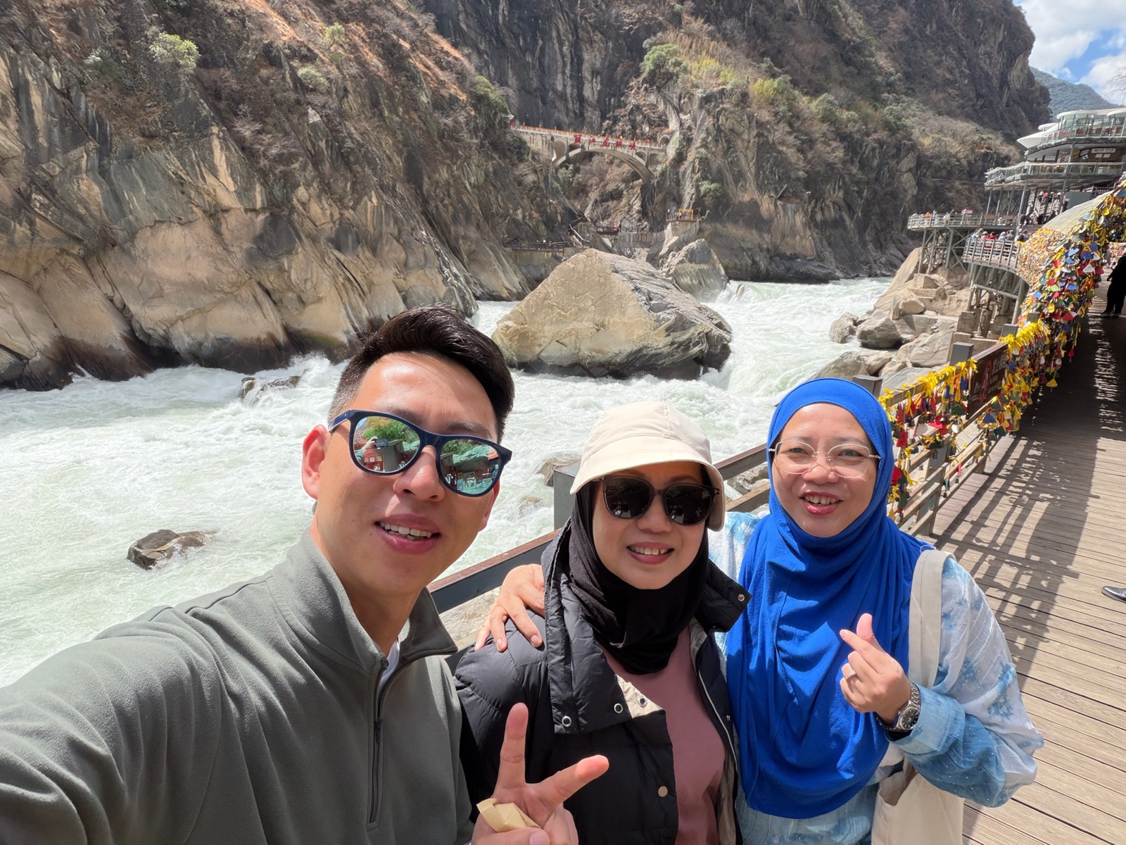 Three travelers taking a selfie above the rushing river at Tiger Leaping Gorge
